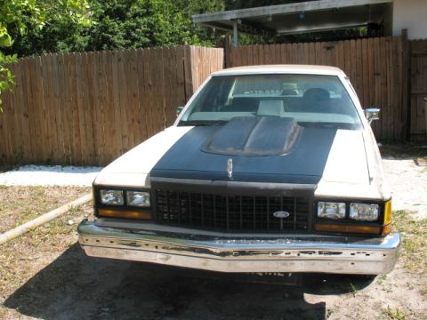 1985 Ford LTD Crown Victoria - Front view of a 1985 Ford Crown Victoria LTD with a prominent hood scoop and dark grille.