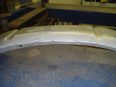 1996 Ford Bronco - Unidentified bent metal car part, possibly from an inner fender, on a workbench.