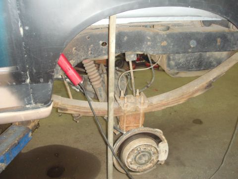 1996 Ford Bronco - Close-up view of the rear suspension and inner fender well of a vehicle, showing leaf springs and brake components.
