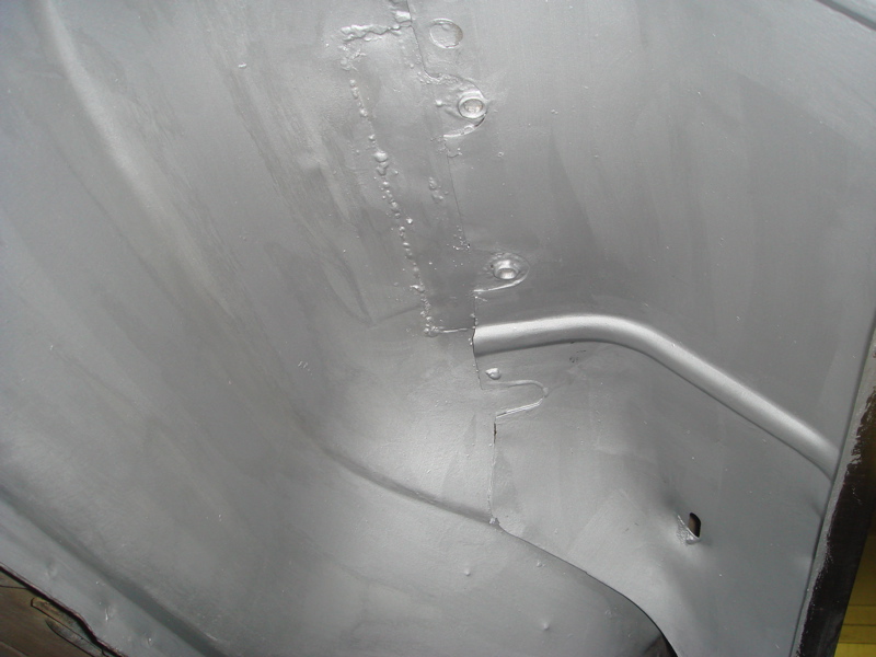 Inner fender panel with visible seams and rivets, painted gray