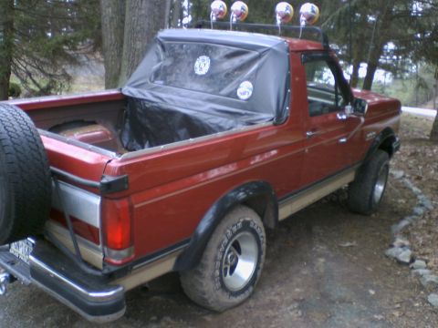 1989 Ford Bronco - This red Ford Bronco, likely from the late 1980s, is equipped with a soft top and spare tire.