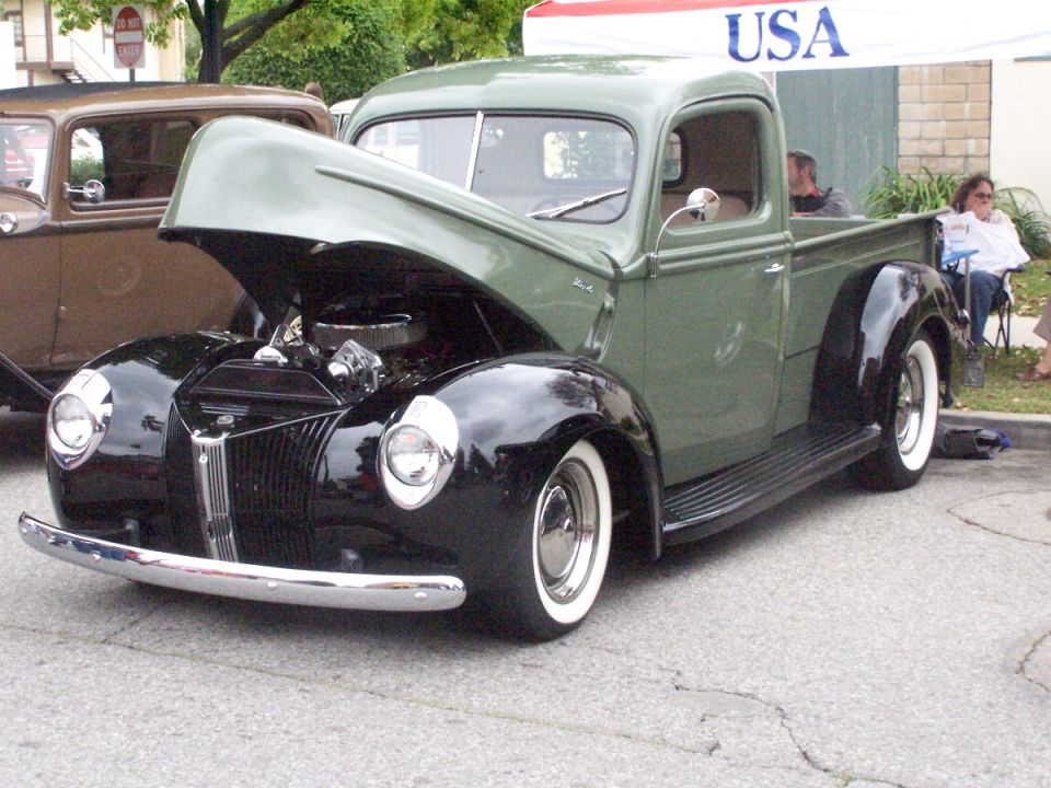 Green and black 1940s pickup truck, hood open, showing engine. Whitewall tires