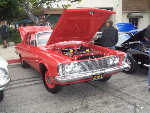 1990 Ford Bronco - A red 1963 Plymouth Belvedere is displayed with its hood open at a car show, revealing the engine and a custom license plate.