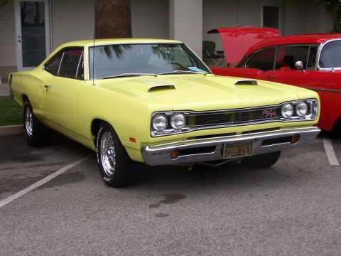 1990 Ford Bronco - A yellow 1969 Dodge Super Bee parked next to a red car at a car show.