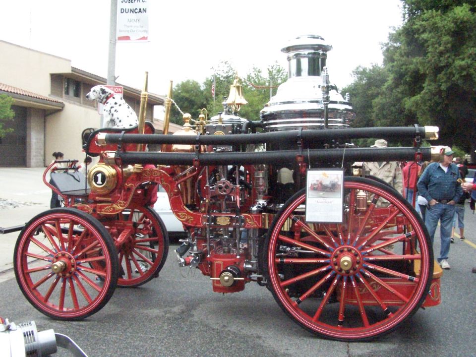 Red antique fire engine with gold trim and a Dalmatian dog, seen from the side