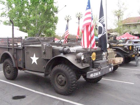 1990 Ford Bronco - Two vintage military trucks are parked side-by-side, one adorned with American flags.