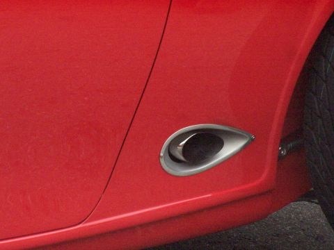 1990 Ford Bronco - Close-up of a red vehicle's side panel, showing a distinctive chrome accent and tire tread.