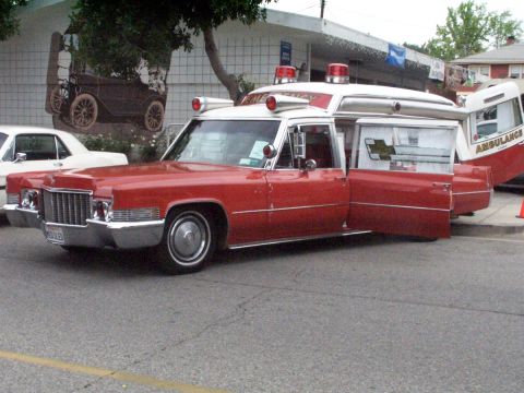 1990 Ford Bronco - This vintage ambulance, likely a Cadillac, is displayed with its doors open, revealing its interior and a distinctive checkered emblem.