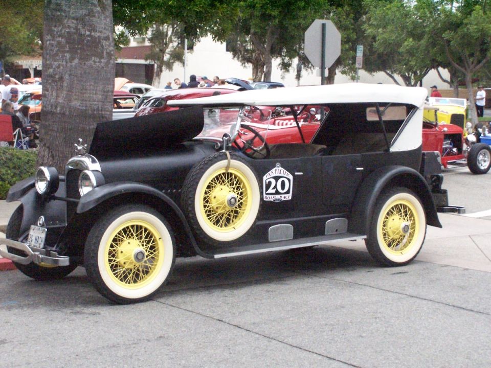 Black touring car with yellow wheels and a white top, side view. Number 20 emblem on door