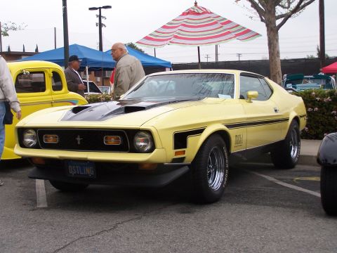 1990 Ford Bronco - A yellow 1971 Ford Mustang Mach 1 is displayed at a car show, parked next to other vehicles.