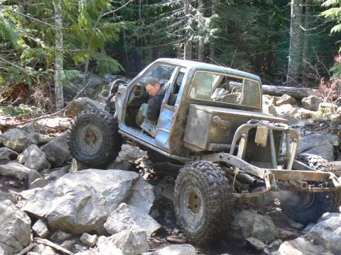 1986 Ford Bronco II - A heavily modified light blue off-road vehicle tackles a challenging rocky trail.