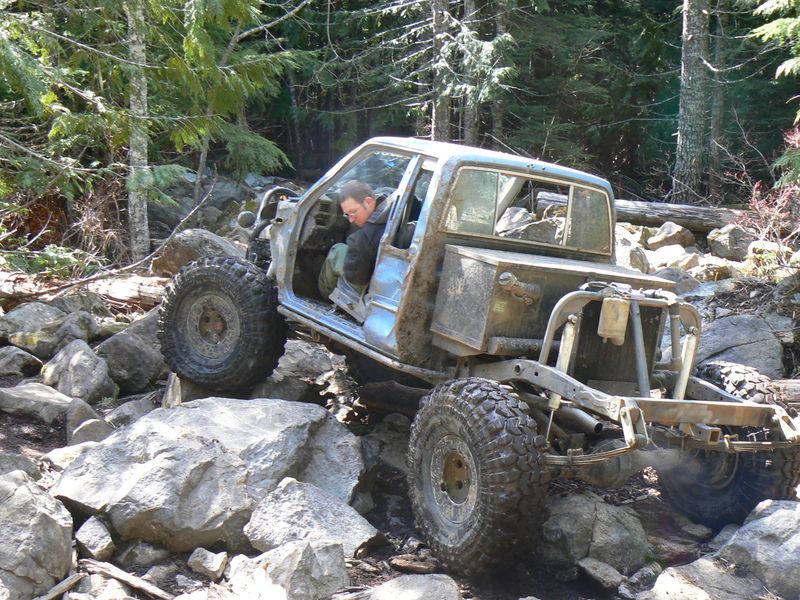 Light blue off-road vehicle with exposed frame and large tires navigating rocky terrain