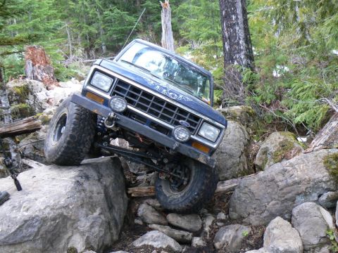 1986 Ford Bronco II - This 1986 Ford Bronco II is navigating a challenging rocky terrain in a forest setting.