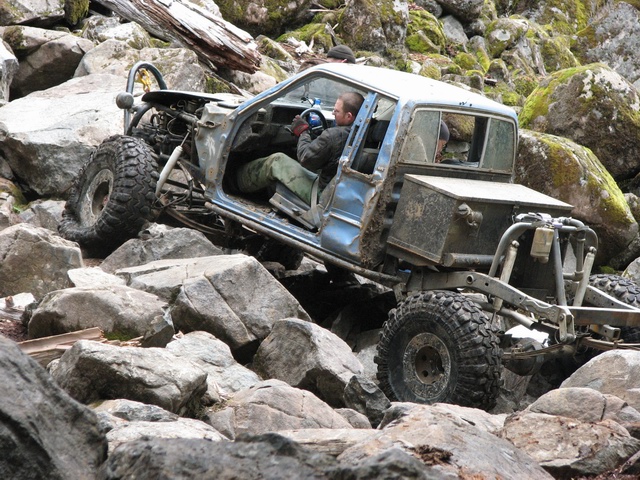 Modified pickup truck with doors removed navigating a rocky terrain