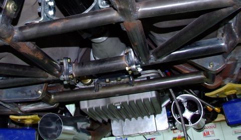 1990 Ford Mustang - The underside of a vehicle shows a custom roll cage, exhaust system, and a large oil pan, suggesting aftermarket modifications.