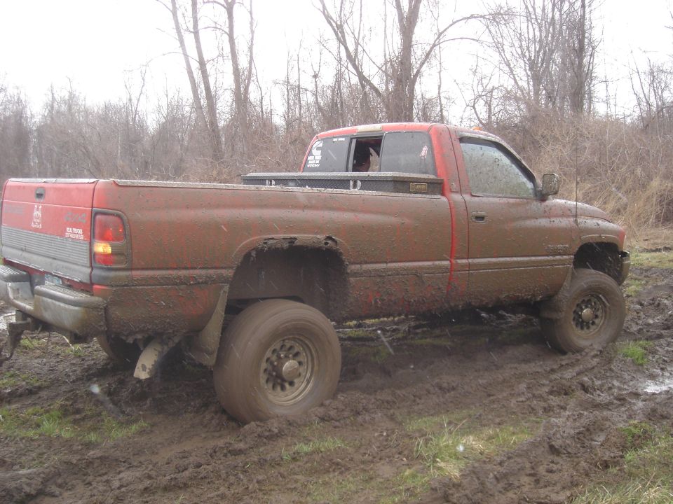 Red pickup truck stuck in mud, side view