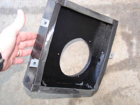 1996 Ford Bronco - A hand holds a black car stereo mounting bracket with a circular cutout, against a concrete background.