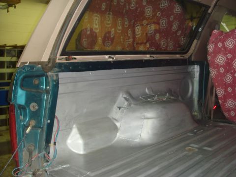 1996 Ford Bronco - The interior of a teal truck bed, viewed from the rear, with a camper shell installed.