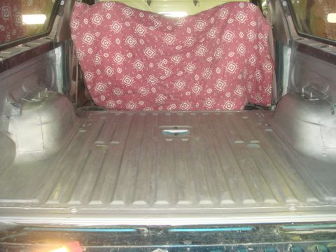 1996 Ford Bronco - Interior view of a truck bed, showing the metal flooring and a patterned cover obscuring the rear.