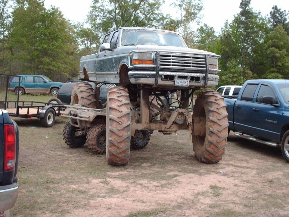 Monster truck with oversized tires, lifted chassis, and a grille that appears to be from a 1992 Ford F-series truck