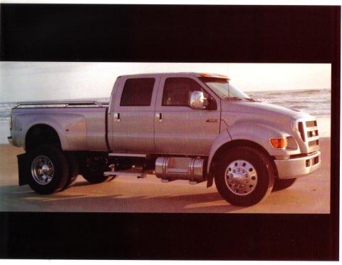 1972 Ford Ranchero - A silver crew cab dually truck is parked on a sandy beach with the ocean in the background.