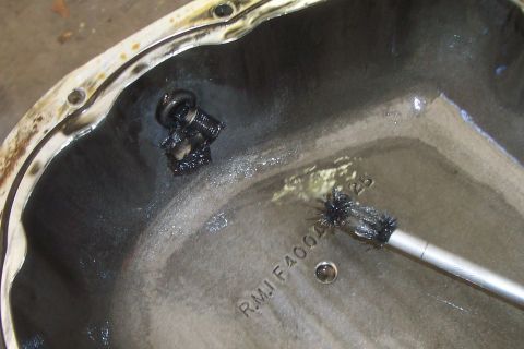 1994 Ford F-150 - Cleaning the inside of a differential cover with a brush. Part number R.M.J F4004 25 is visible.