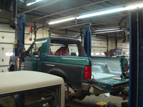 1996 Ford Bronco - Green 1996 Ford Bronco in a garage, lifted for repairs with the tailgate down.