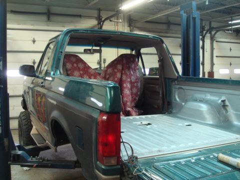 1996 Ford Bronco - The rear of a green Ford Bronco is shown with the bed area exposed and seats covered.