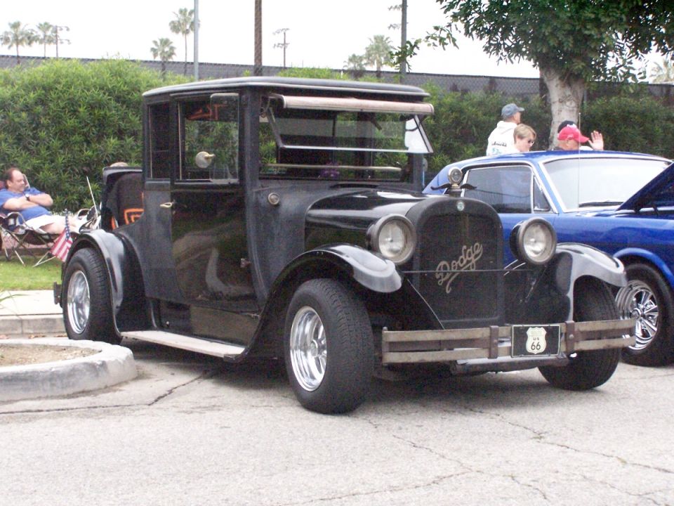Black vintage Dodge car with Route 66 plate, parked next to a blue car
