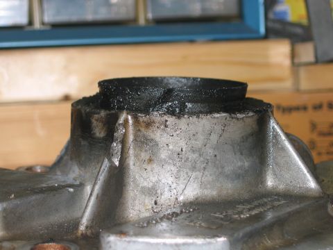 1992 Ford Bronco - Close-up of a cast aluminum engine or transmission component with a machined cylindrical bore capped by a black, carbon-caked seal or bushi…