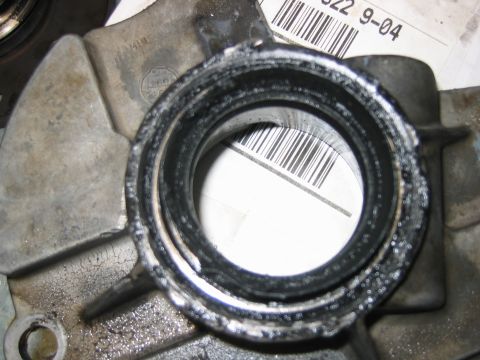 1992 Ford Bronco - Close-up of a grease-blackened round seal bore on a bare aluminum housing, with crusted black residue around the seal lip and a barcode lab…