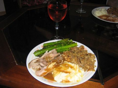 1995 Ford Bronco - A meal of turkey, mashed potatoes, asparagus, and stuffing is served with a glass of red wine on a dark table.