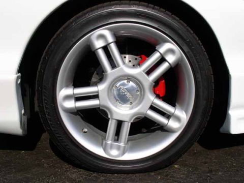 1996 Ford Probe - Close-up of a silver five-spoke wheel with a red brake caliper and a 'Firehawk' center cap.