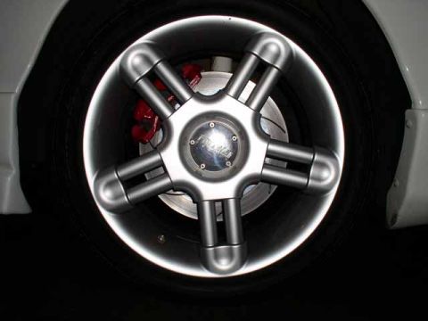 1996 Ford Probe - Close-up of a custom wheel with a five-spoke design, revealing a red brake caliper behind the spokes.