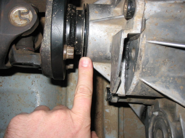 Underside drivetrain U-joint yoke and output flange with finger pointing to seal area