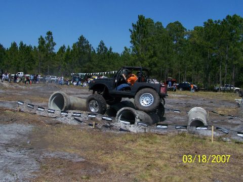 1989 Ford Bronco - An off-road vehicle tackles a challenging obstacle course with concrete pipes and dirt terrain.