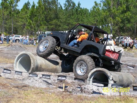 1989 Ford Bronco - An off-road SUV tackles a challenging obstacle course with spectators watching.