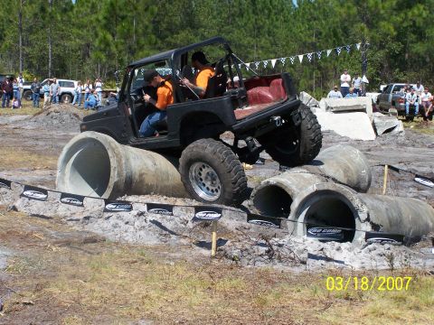 1989 Ford Bronco - Off-road vehicle tackles a challenging obstacle course large concrete pipes.