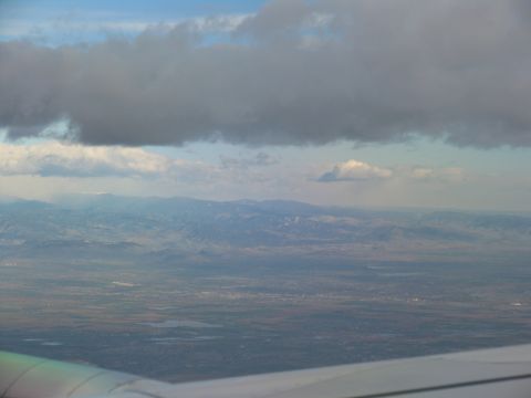 1995 Ford C-350 (Centurion Conversions) - Looking down from an airplane at clouds, mountains, and a distant town.