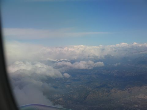 1995 Ford C-350 (Centurion Conversions) - View from an airplane window shows clouds obscuring a mountainous landscape below.