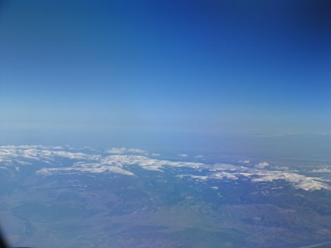 1995 Ford C-350 (Centurion Conversions) - View from an airplane window shows a vast expanse of mountains with snow on their peaks.