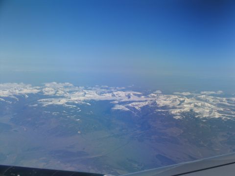 1995 Ford C-350 (Centurion Conversions) - An aerial perspective captures the grandeur of snow-covered mountain ranges beneath a vast expanse of blue sky.