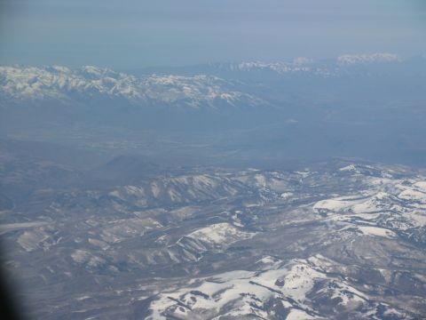 1995 Ford C-350 (Centurion Conversions) - Expansive mountain range seen from an airplane, with snow dusting the peaks and slopes.