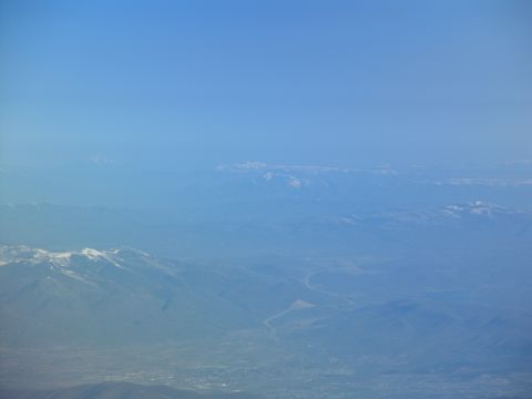 1995 Ford C-350 (Centurion Conversions) - View from airplane window shows distant snow-capped mountains and a valley below.