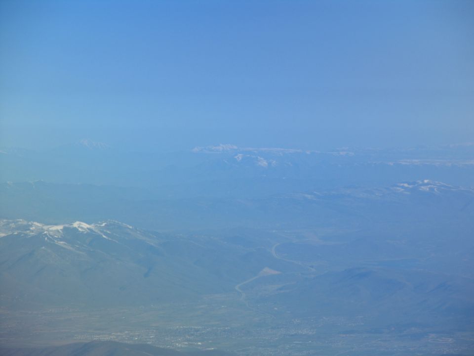 Aerial view of hazy mountains and a valley with a winding river under a clear blue sky