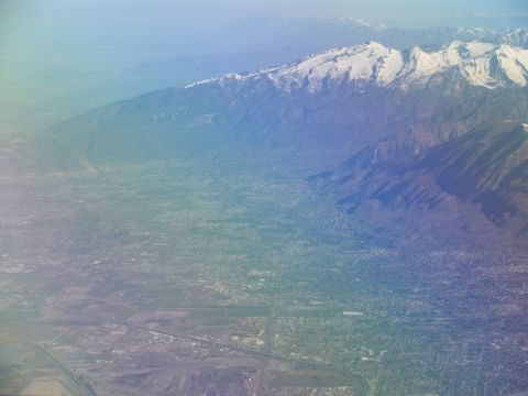 1995 Ford C-350 (Centurion Conversions) - An aerial perspective captures a vast valley bordered by , snow-dusted mountains under a hazy sky.