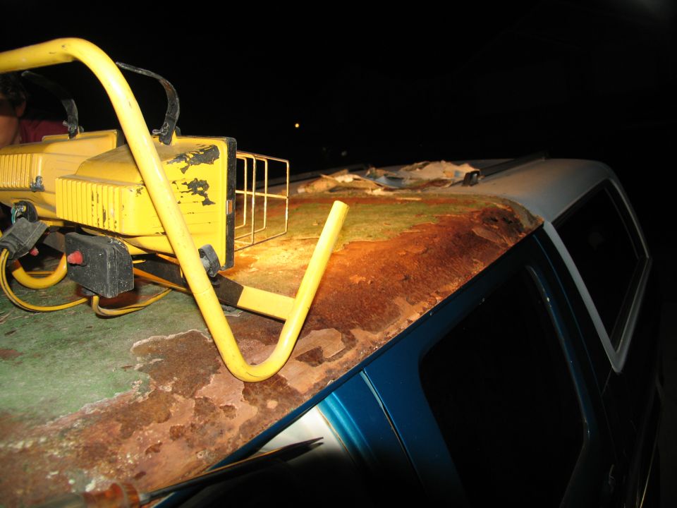 Rusted roof of a blue van with a yellow work light