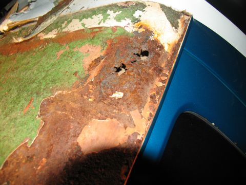 1995 Ford C-350 (Centurion Conversions) - Detail of a heavily rusted metal panel with peeling paint and visible holes.