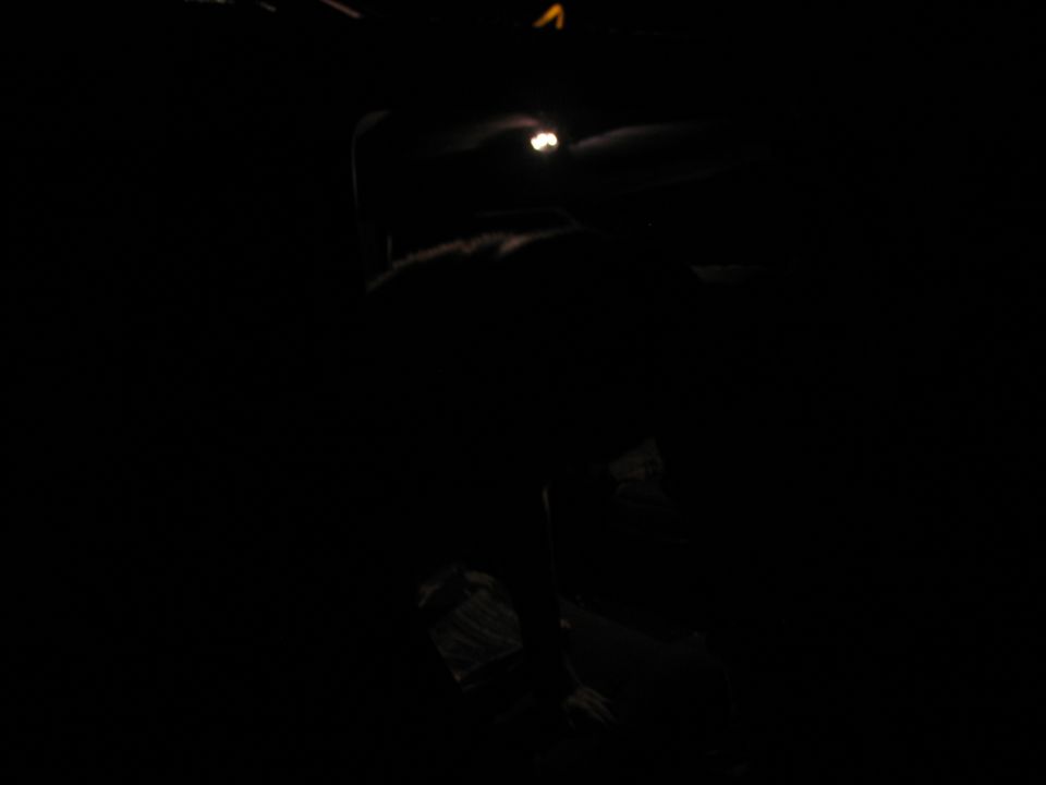 Interior of a dark vehicle at night, with a faint light visible on the dashboard