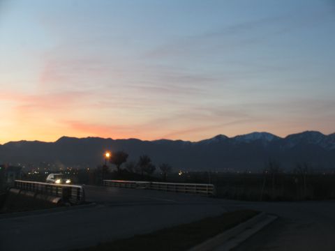 1995 Ford C-350 (Centurion Conversions) - A car drives across a bridge at sunset, with a mountain range visible in the distance.